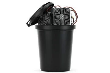 ASIC de minage de Bitcoin posé sur une poubelle noire, symbole du mythe des déchets électroniques